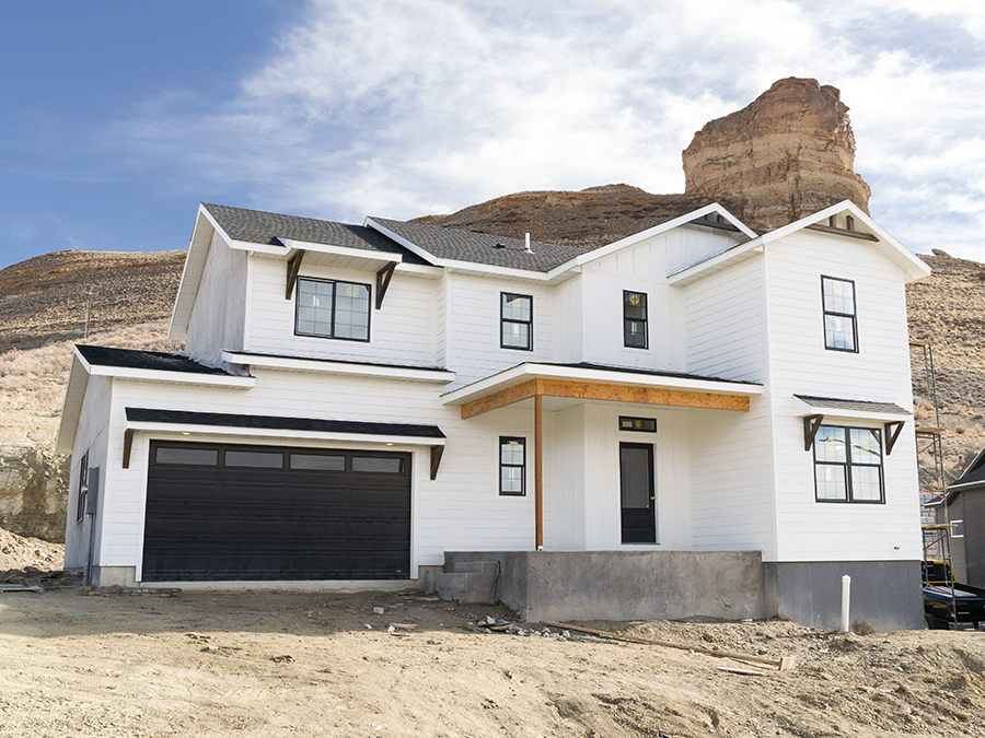 Exterior photo of charming 2-story home with 2-car garage, front porch, white siding and wood accents